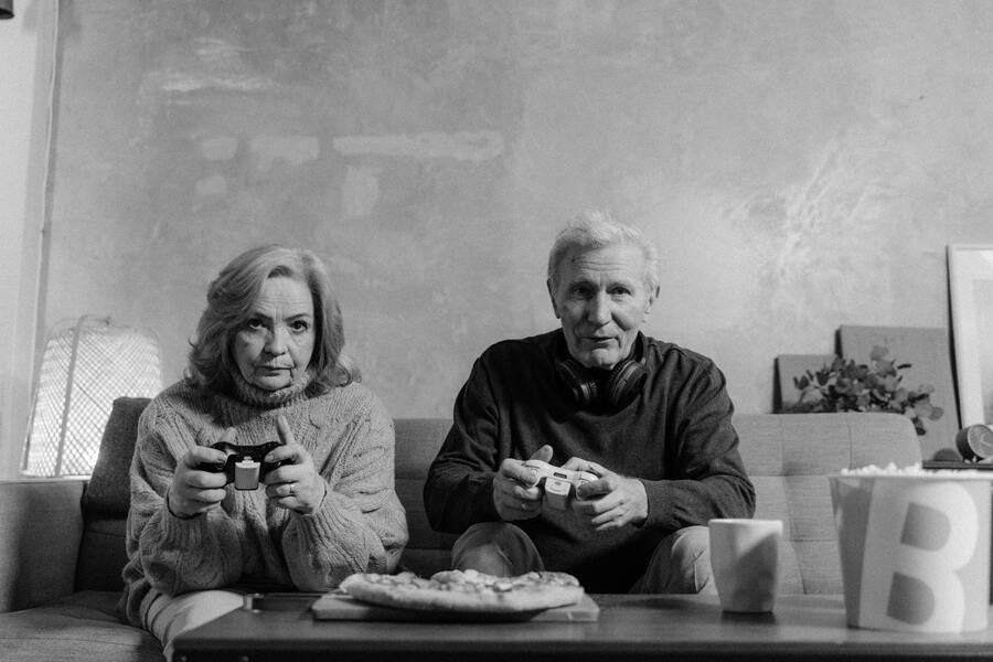 Grayscale photo of elderly man and woman playing video game